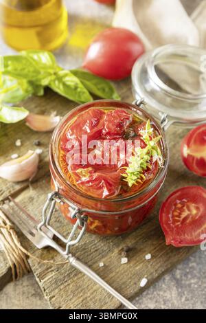 Gesunde hausgemachte fermentierte Lebensmittel. Sonnengetrocknete Tomaten im Glas mit Gewürzen und Kräutern. Hauswirtschaftslehre, Herbsternterhaltung Stockfoto