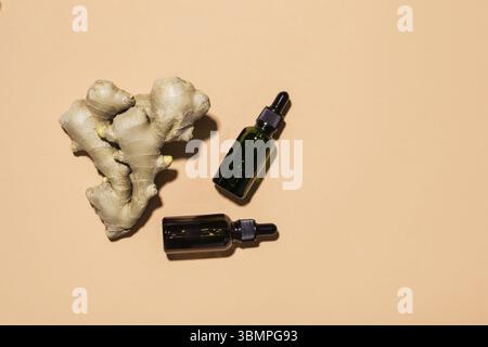 Ätherisches Bio-Ingweröl in dunkler Glasflasche und Ingwerwurzel, Kopierraum Stockfoto