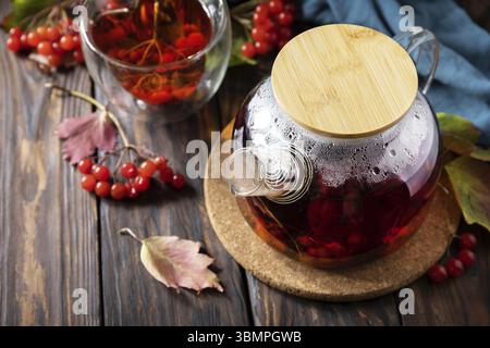 Herbsttee, Beerenvitamingetränk der Saison. Viburnum und Tasse gesunden Viburnum-Tee auf einem hölzernen Hintergrund. Kopierbereich Stockfoto