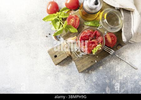 Sonnengetrocknete Tomaten im Glas mit Gewürzen und Kräutern. Gesundes, hausgemachtes fermentiertes Essen. Hauswirtschaft, Herbsternteerhaltung. Ansicht von oben. Kopie s Stockfoto
