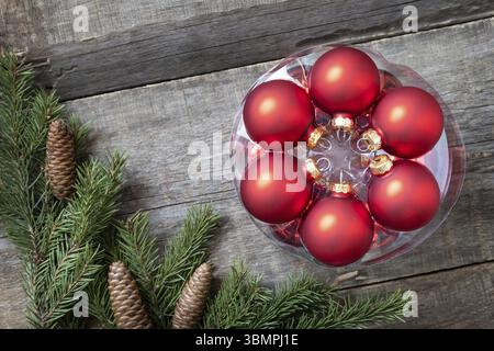 Postkartendesign im Vintage-Stil. Rote Weihnachtskugeln Dekorationen auf hölzernem Hintergrund mit Kopierraum Stockfoto