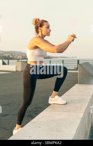 Fitte Frau, die beim Training im Freien am Wasser Steps-ups-Übungen durchführt. Stockfoto