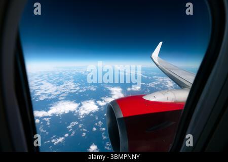 Wunderschöne Aussicht vom Flugzeugfenster auf die Landschaft über den Wolken und das Meer. Ansicht des Flügels eines Flugzeugs mit Düsenantrieb. Stockfoto