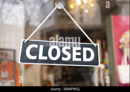 Ein geschlossenes Schild mit einem Saugnapf ist am Glas der Eingangstür einer Modeboutique angebracht Stockfoto