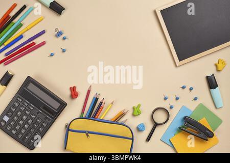 Helles, flaches Lay-Foto eines Arbeitsplatzes mit Schulzubehör, wie drei Marker, farbige Bleistifte, gelbe Bleistiftetui, Filzstifte, Lupe, äh Stockfoto