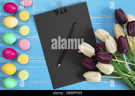 Ostereier und Tulpen auf blauen Holzplanken. Draufsicht. Speicherplatz kopieren Stockfoto