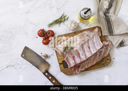 Rohe Kalbsbrust Rippchen Fleisch mit Gemüse und Gewürzen auf kurzen Ersatzrippchen zum Kochen auf Marmorplatte. Draufsicht, flach Stockfoto