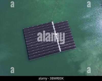 Aus der Vogelperspektive des schwimmenden Solarparks mit vielen Solarpaneelen auf dem türkisfarbenen See Stockfoto