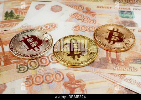 Nahaufnahme von Bitcoin-Münzen auf 5000 russischen Rubel-Banknoten. Kryptowährung BTC Stockfoto
