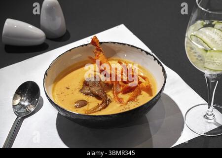 Nahaufnahme einer leckeren Cremesuppe mit Fleisch auf einem schwarzen Tisch mit einem Glas Wein, Blick von oben. Gourmetmenü, Restaurant serviert. Kochen im Geheimen Stockfoto