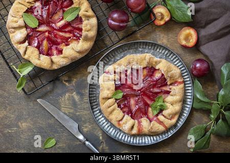 Veganes vegetarisches Dessert, Pflaumengalette mit Mandeln. Gesunder hausgemachter Vollkornobstkuchen, süße Krostata auf einem rustikalen Tisch. Blick von oben Stockfoto