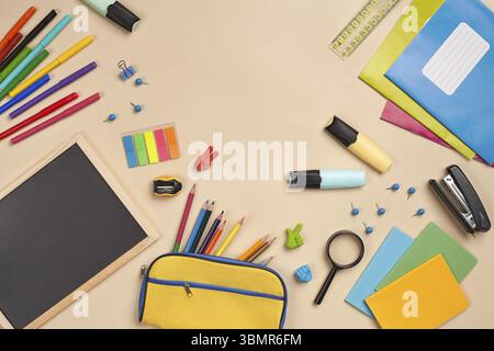 Helles, flaches Lay-Foto eines Arbeitsplatzes mit Schulzubehör, wie drei Marker, farbige Bleistifte, gelbe Bleistiftetui, Filzstifte, Lupe, äh Stockfoto
