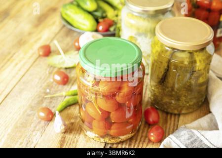 Gesalzene eingelegte Gurken und Tomaten, konserviert in Glasbehältern. Hauswirtschaft, Herbsternteerhaltung. Gesundes, hausgemachtes fermentiertes Essen. Cop Stockfoto
