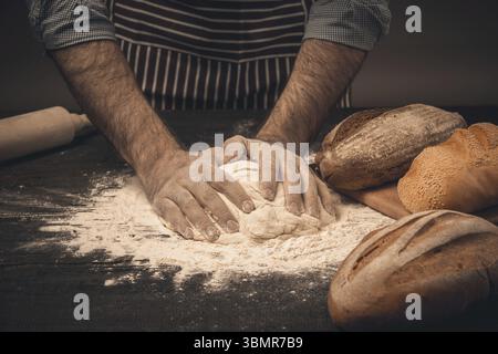 Männliche Hände kneten Sie den Teig. Koch Kochen Brot und Brötchen Stockfoto