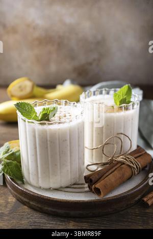 Bananen-Smoothie mit Zimt in Trinkglas auf hölzernem Hintergrund. Entgiftungsmenü. Kopierbereich Stockfoto