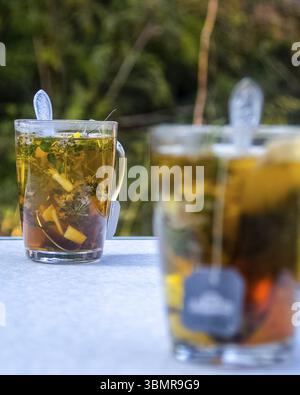 Transparenter Becher mit Tee. Tee in einer Tüte zubereiten. Kräutertee brühen. Kräutertee Stockfoto