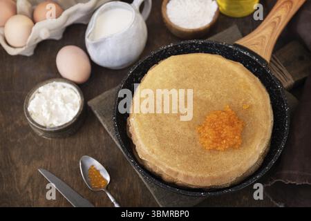 Pfannkuchen traditionelle russische Küche. Dünne Pfannkuchen mit rotem Kaviar auf einem Holztisch Stockfoto