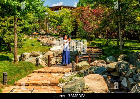 Im Galitsky Park in Krasnodar steht eine Frau auf einer Brücke und macht ein Selfie Stockfoto