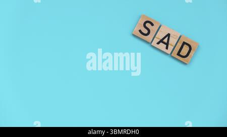 Saisonale affektive Störung - Text von Holzblöcken auf blauem hellem Hintergrund. Konzept von Depressionsstress und Angst. TRAURIGES Wohlbefinden Stockfoto