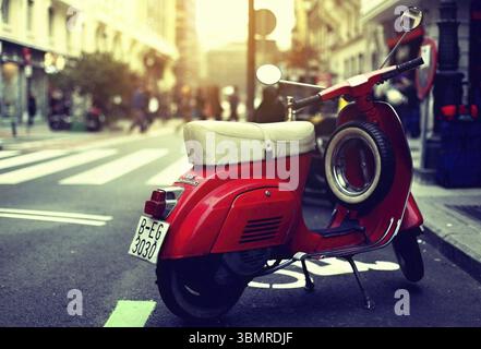 Roter Vintage-Roller parkte an der Seite einer europäischen Straße während eines wunderschönen Sonnenuntergangs Stockfoto