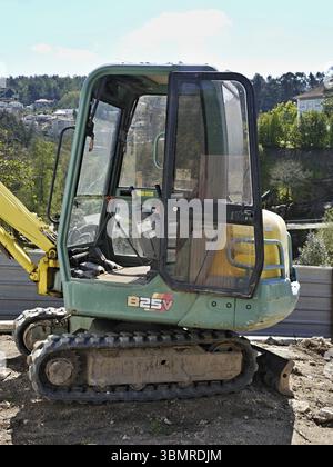 Kleiner Bagger mit offener Tür, auf einer Baustelle geparkt, einsatzbereit Stockfoto