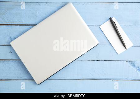 Graues Notebook und Papier-Notizbuch mit schwarzem Stift auf blauem Holzhintergrund. Die Aussicht von oben Stockfoto