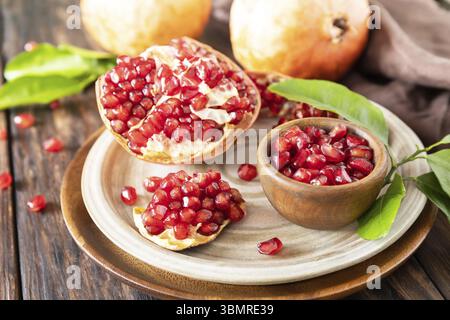 Reife saftige Granatapfelfrüchte in einer Holzschale auf einem rustikalen Tisch. Ernährung und gesunde Ernährung Stockfoto