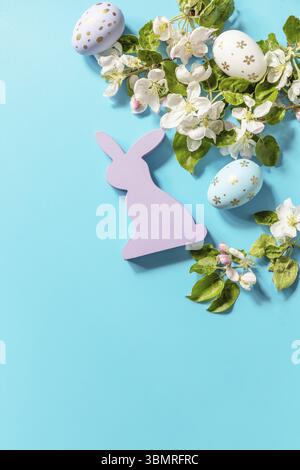 Ostergemisch mit bunten Eiern, Holzhasen und Frühlingsblumen auf blauem Hintergrund. Frühlingskonzept, Blumenzusammensetzung. Grußkarte. Anzeigen Stockfoto