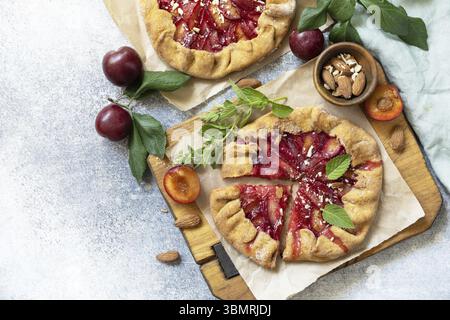 Plum Galette. Gesunder hausgemachter Vollkornfruchtkuchen (Galette) mit Pflaumen und Mandeln, veganes vegetarisches Dessert auf einem Steintisch. Blick von oben. Kopieren Stockfoto