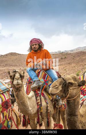 Petra, Jordanien - 26. Oktober 2015: Beduinen auf einem Kamel. Ein Spaziergang auf einem Kamel. Der Service für Touristen. Reiseleiter. Die Regenzeit in Jordanien. Petra ist an Stockfoto