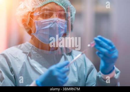 Der Arzt oder Labortechniker Wissenschaftler in PSA persönliche Schutzausrüstung hält Leertest, Impfinjektion, Weltimunisierung und Internation. Stockfoto