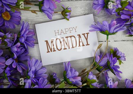 Happy Monday Text mit Blumendekoration auf hölzernem Hintergrund Stockfoto