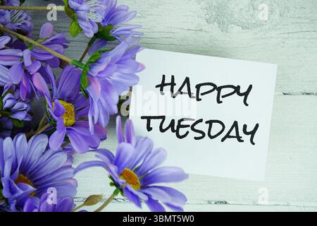 Happy Tuesday Text mit Blumendekoration auf hölzernem Hintergrund Stockfoto