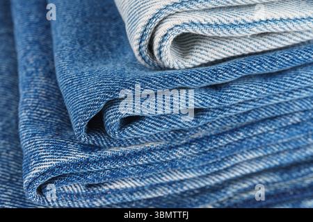 Ein Stapel gefalteter Textilien, verschiedene Farbtöne von Jeansstoff und Denim-Stoff werden im Ladenlokal übereinander gestapelt und zeigen verschiedene Textilien Stockfoto