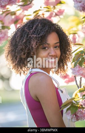 Eine junge Afroamerikanerin mit natürlich lockigem Haar lächelt in die Kamera. Stockfoto