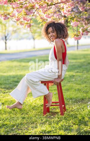 Eine junge Afroamerikanerin mit natürlich lockigem Haar lächelt in die Kamera. Stockfoto
