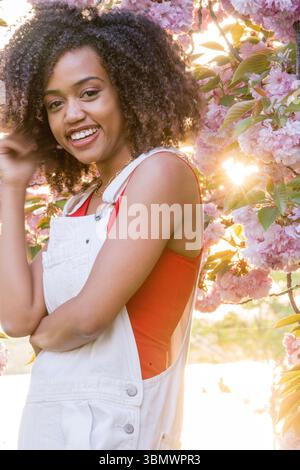 Eine junge Afroamerikanerin mit natürlich lockigem Haar lächelt in die Kamera. Stockfoto