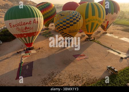 Luftaufnahme einer Gruppe von Heißluftballons, die sich auf die Tour durch das Tal der Könige bei Sonnenaufgang vorbereiten, Luxor, Ägypten Stockfoto