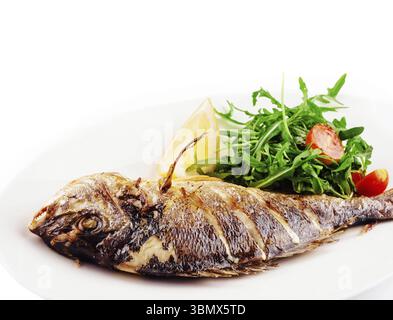 Essen Stillleben, gebackener Seebrassen Fisch mit Rucola Salat und Tomaten Stockfoto