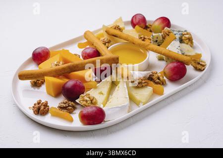 Stillleben, Käseplatte mit Honig, Nüssen und roten Trauben Stockfoto