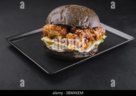 Stillleben, Burger mit gebratenen Hähnchenstreifen auf schwarzem Tablett Stockfoto