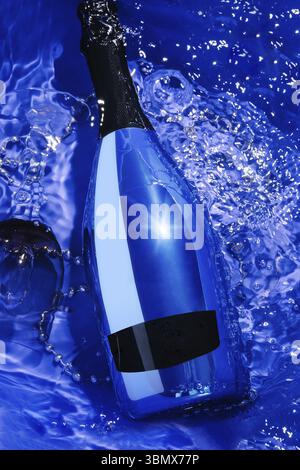 Stillleben, blaue Sektflasche und Glas in Wasser Stockfoto