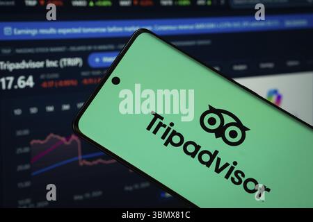 Dhaka, Bangladesch- 22. Juni 2025: Das TripAdvisor-Logo wird auf einem Smartphone-Bildschirm angezeigt, wobei eine Website mit einem Bestandsdiagramm auf einem Computerbildschirm im zu sehen ist Stockfoto
