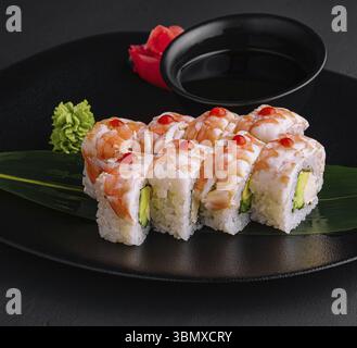 Stillleben von Lebensmitteln, Sushi-Rolle bedeckt mit Garnelenfleisch auf schwarzer Keramikplatte Stockfoto
