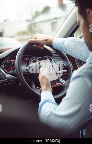 Man-fahrer mittels Smart Phone im Auto. Stockfoto
