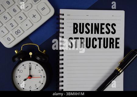 Text der Geschäftsstruktur auf Notizblock mit Taschenrechner und Wecker auf marineblauem Hintergrund geschrieben Stockfoto