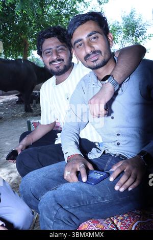 Zwei junge Indianer sitzen draußen und lächeln für die Kamera Stockfoto