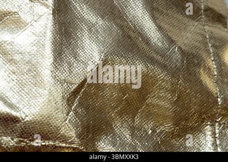 Goldener Glitzer-Hintergrund mit Öltuchbeschaffenheit, abstraktes Material mit Glanz und Falten für Hintergründe und Vorlagen, goldener Hintergrund Stockfoto