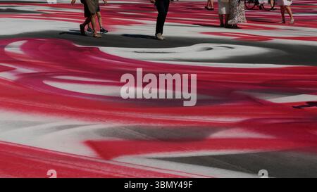 Abstrakte Asphalt-Kunstinstallation mit Rot-weiß-Design mit Fußgängern Stockfoto