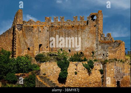 Honigfarbene Ruinen des mittelalterlichen Castello del Rivellino oder der Burg Rivellino, ein befestigter Palast aus der Mitte der 1200er Jahre, erbaut auf einer terrassenakropolis der antiken Etrusker. Einst Zentrum der bürgerlichen und justiziellen Macht in der Toskana, Provinz Viterbo, Latium, Italien. Die Festung liegt inmitten der antiken etruskischen und römischen Überreste der etruskischen Stadt Tuscana, die im 7. Jahrhundert v. Chr. gegründet wurde. Stockfoto